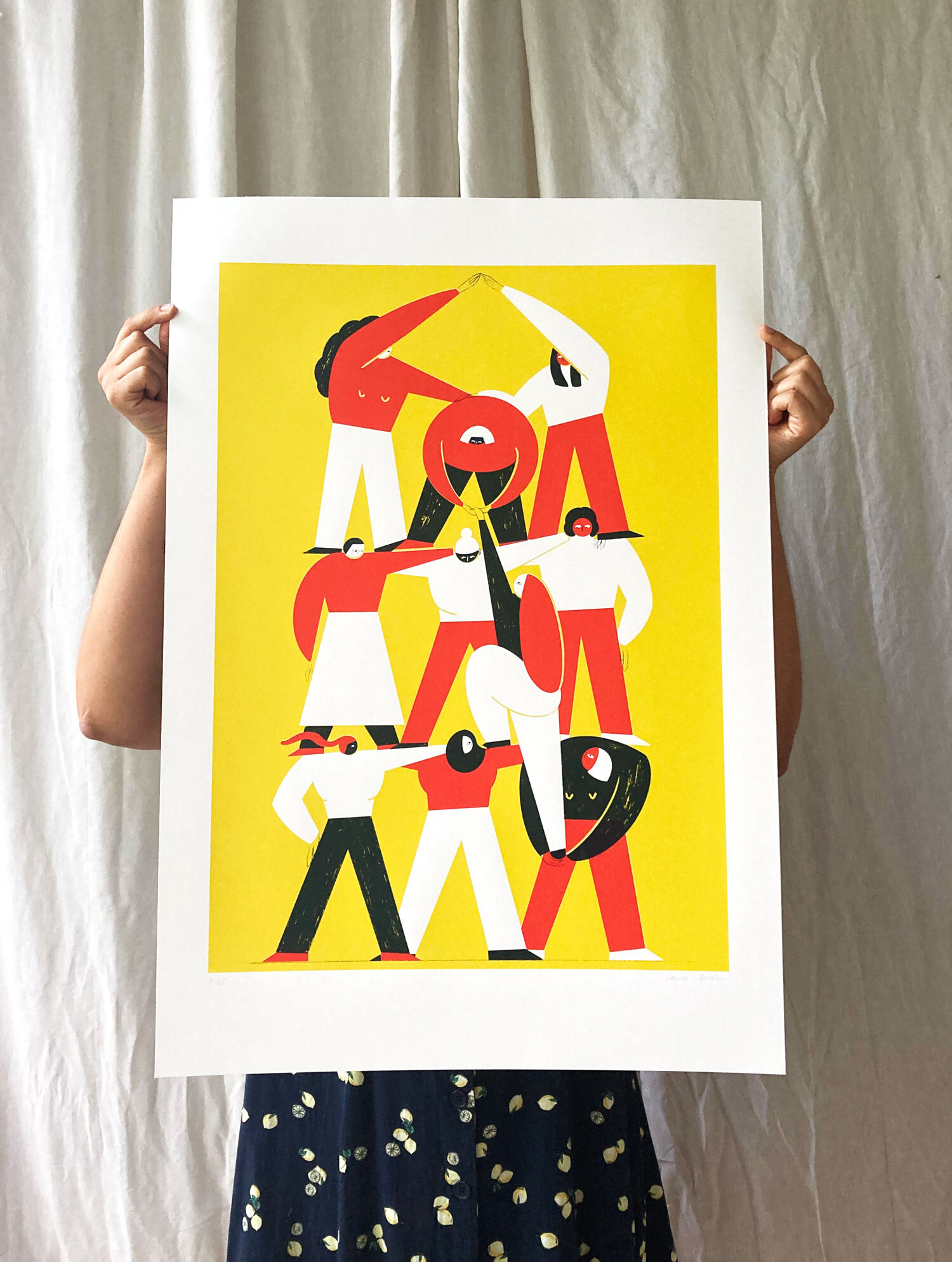 Siebdruck, gehalten von zwei Händen vor einem weißen Vorhang. Auf dem Druck: drei mal drei übereinander gestapelten Flinta-Personen, sowie eine, die gerade ganz nach oben steigt. Gelber Hintergrund, die Personen in weiß, rot, dunkelblau.