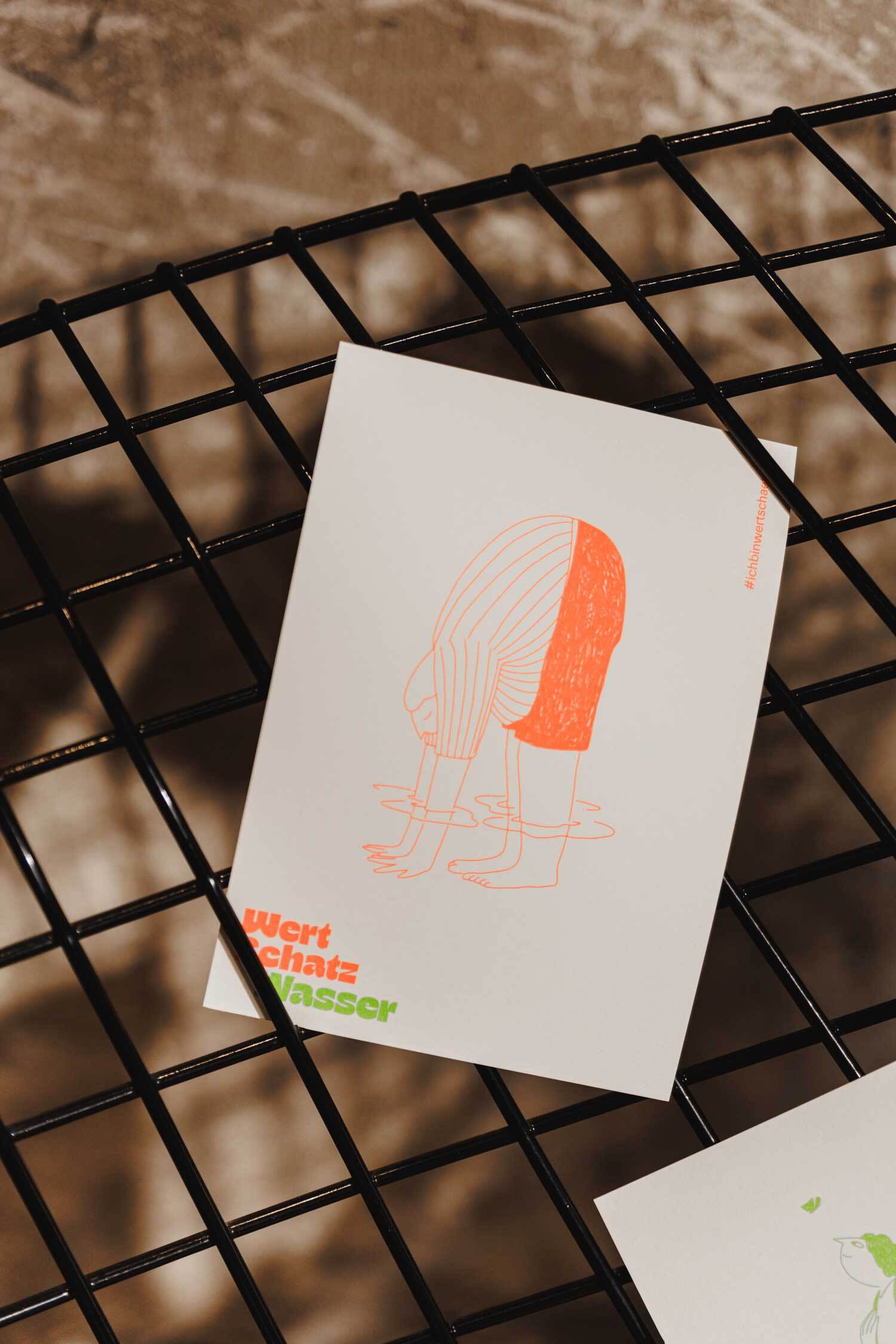 Postkarte steckt in einem Gitter. "Wertschatz Wasser"