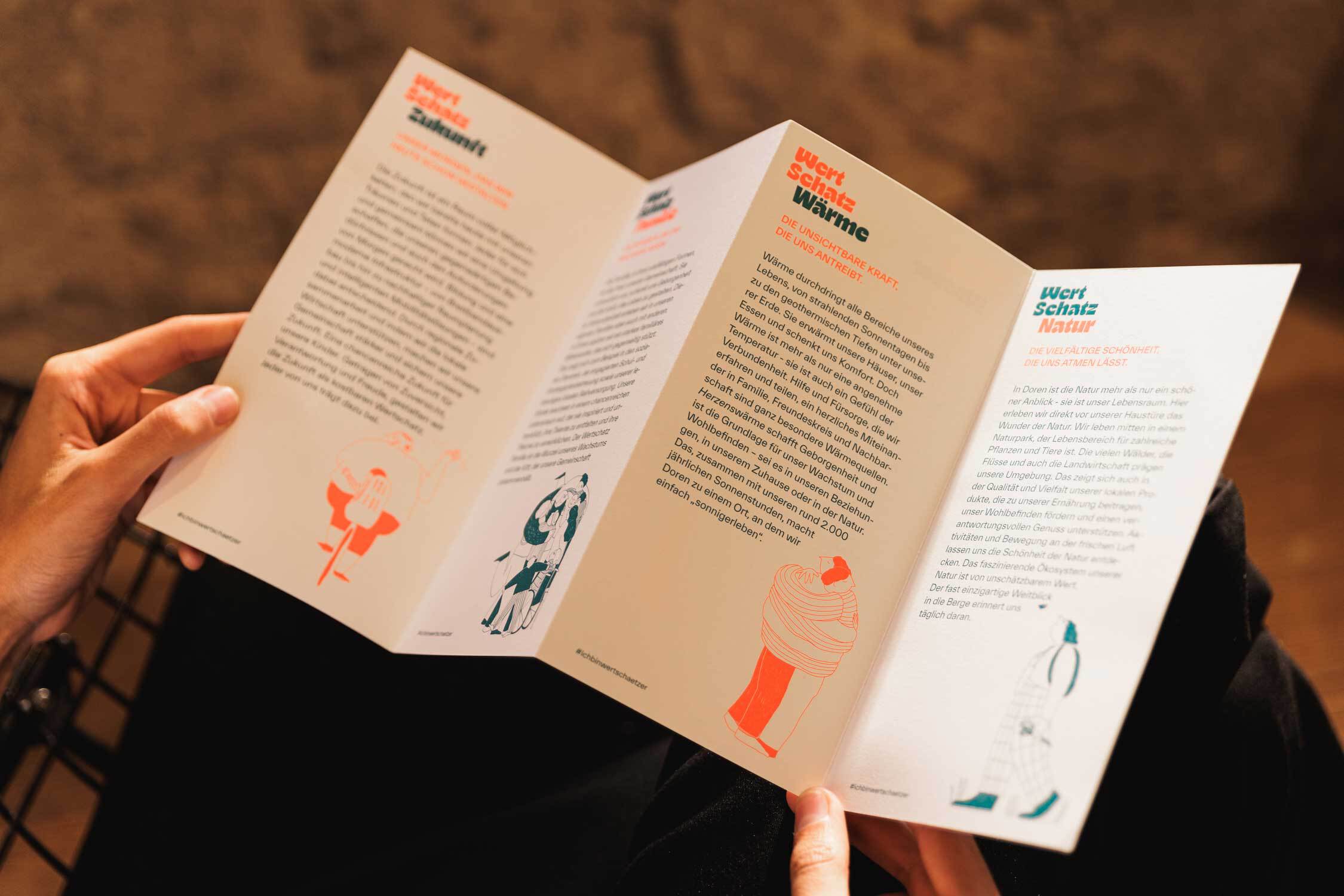 Flyer/Leporello aufgeschlagen in den Händen einer Person.