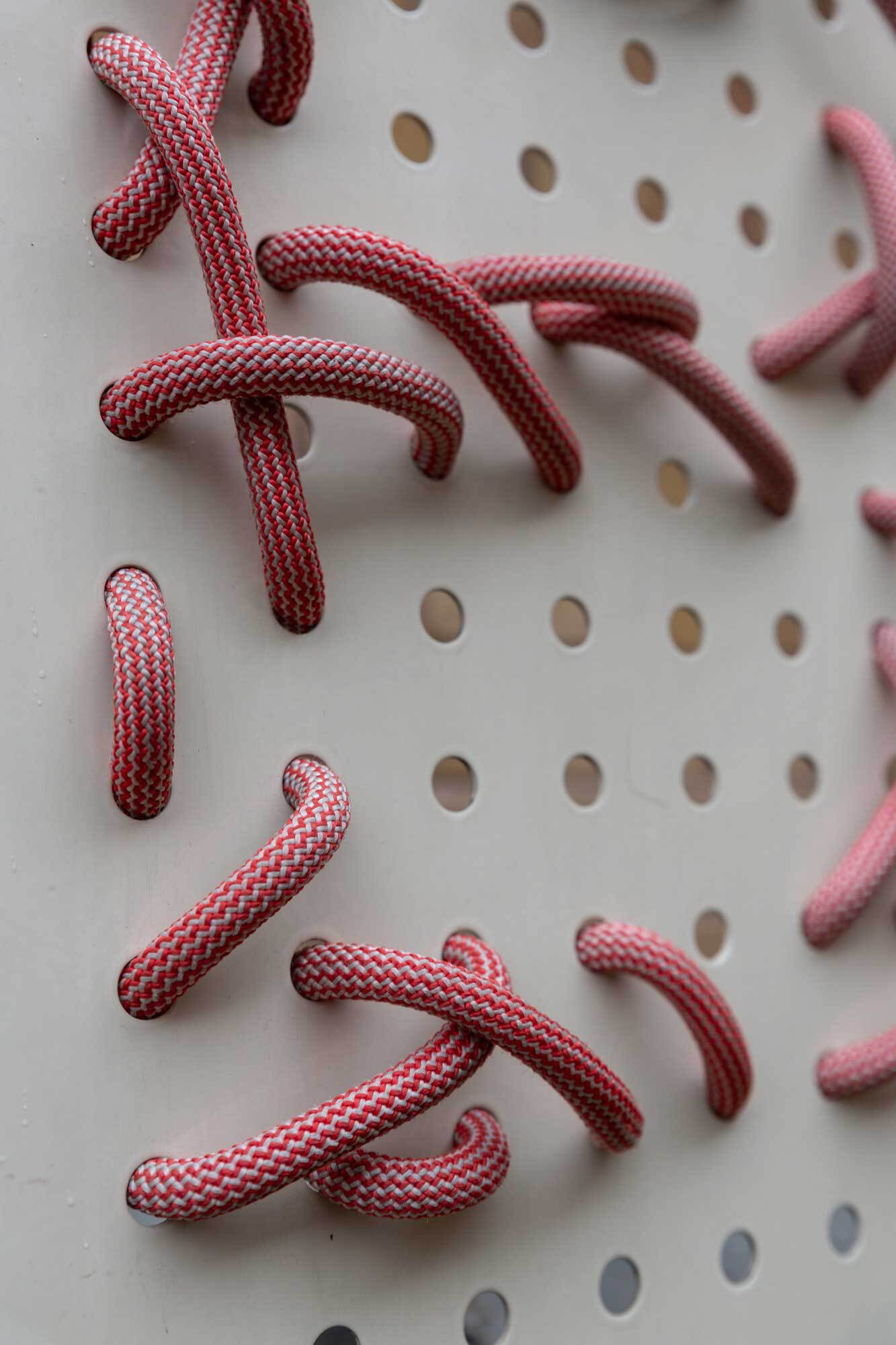 Detail einer Lochplatte durch die ein Kletterseil gefädelt ist.